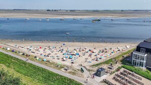 A beach with tents and people, a sandy shore, and boats in the water. - Apartment in Sint-Annaland near Marina (Sint-Annaland)