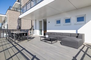 Eine moderne Terrassenanlage im Freien mit Esstisch, einer Couch und einem Couchtisch.
