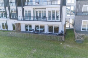 Ein mehrstöckiges Wohngebäude mit Balkonen, großen Fenstern und einem Rasen.