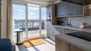 A modern kitchen with a large window, sliding doors, and a view of the city.