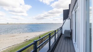 A balcony with a view of a beach and water.