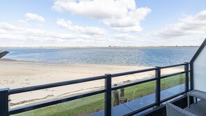 A view from a balcony overlooking a beach with a clear sky.