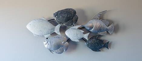 A collection of metallic fish sculptures on a plain wall.