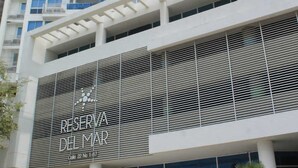 Un edificio moderno de gran altura, con balcones y ventanas amplias. El edificio muestra un letrero que dice "RESERVA DEL MAR Calle 22 No 1-7".