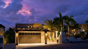 A modern house with a garage, a balcony, and a staircase leading to the entrance. - Casa Famlee - Duplex House(sleeps 8) with Pool & Hot Tub in Cabo San Lucas! (Cabo Bello)