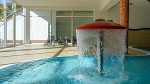 A swimming pool with a water fountain, indoor seating area, and large windows. - Elegant eingerichtete Ferienwohnung (Granzow)