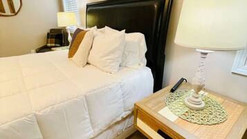 A hotel room with a large bed, a bedside table with a lamp, and a painting on the wall.