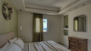 A bedroom with a bed, a dresser, a mirror, a window with curtains, and a wall decoration. - Superior ενός υπνοδωμάτιού, Erietta Apartments (Zakynthos)