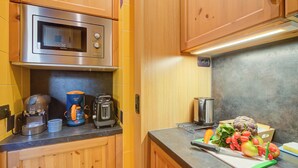 Een keuken met houten kastjes, een magnetron, een koffiezetapparaat en een broodrooster.
