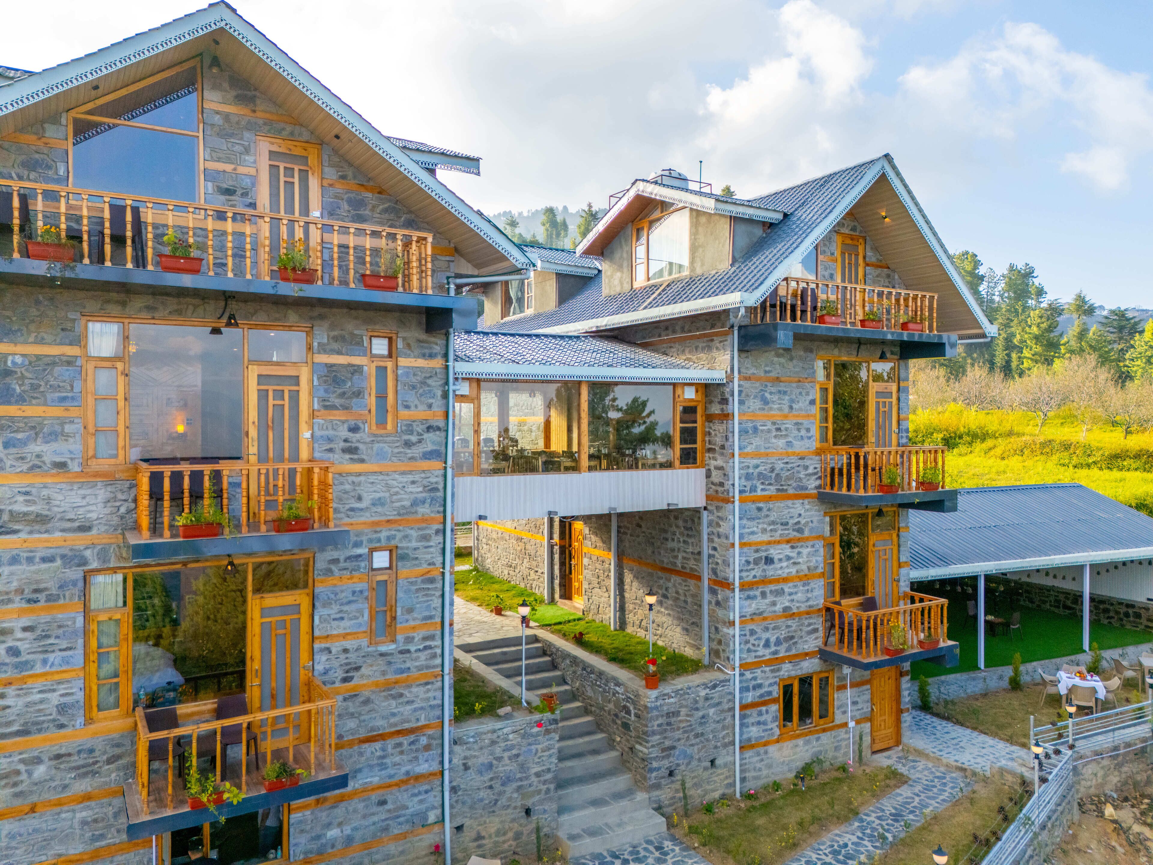 Un bâtiment en pierre doté de nombreux balcons et d’espaces aménagés pour s’asseoir à l’extérieur.
