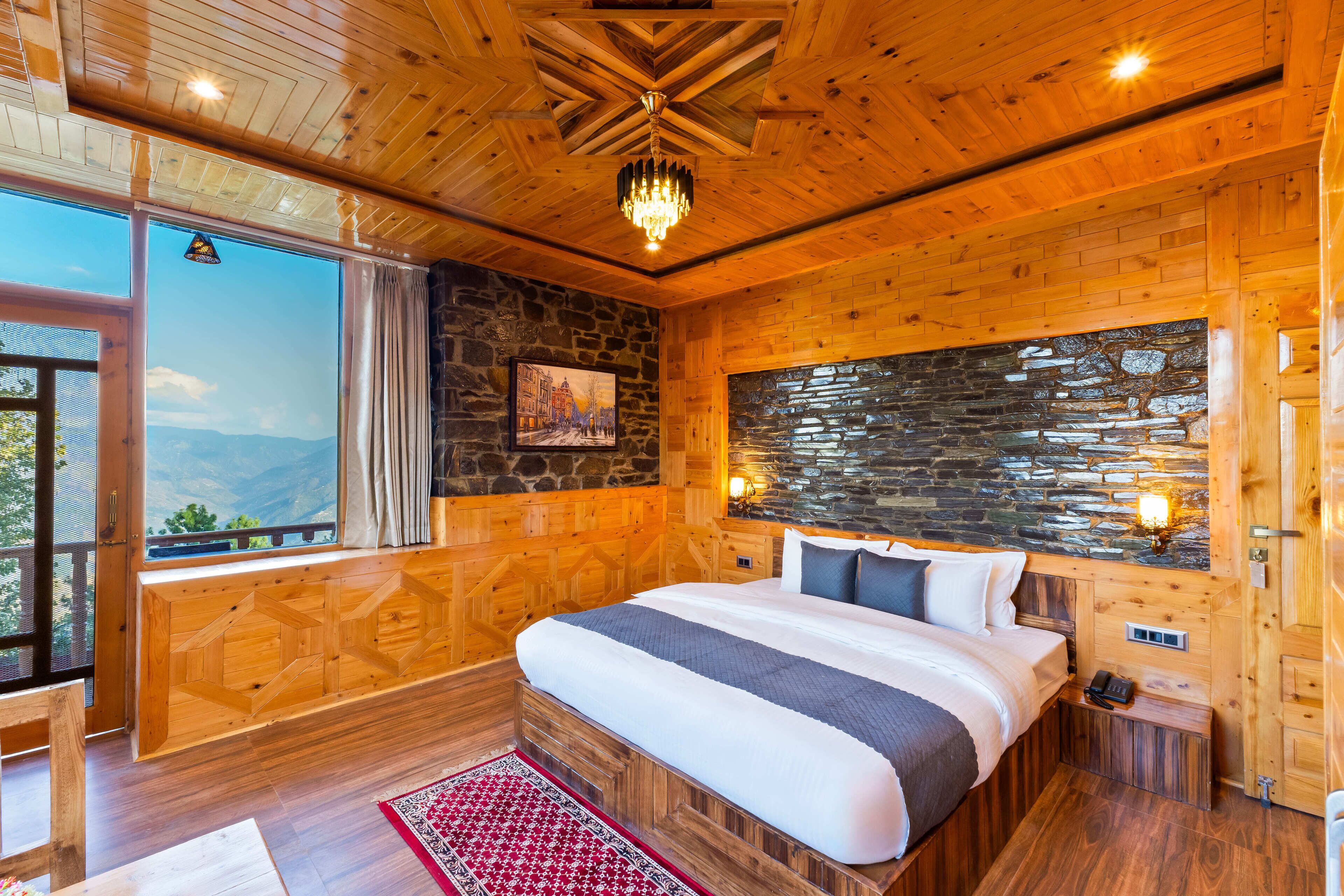 Un dormitorio de madera con una cama grande, un muro de piedra y una ventana con vistas.