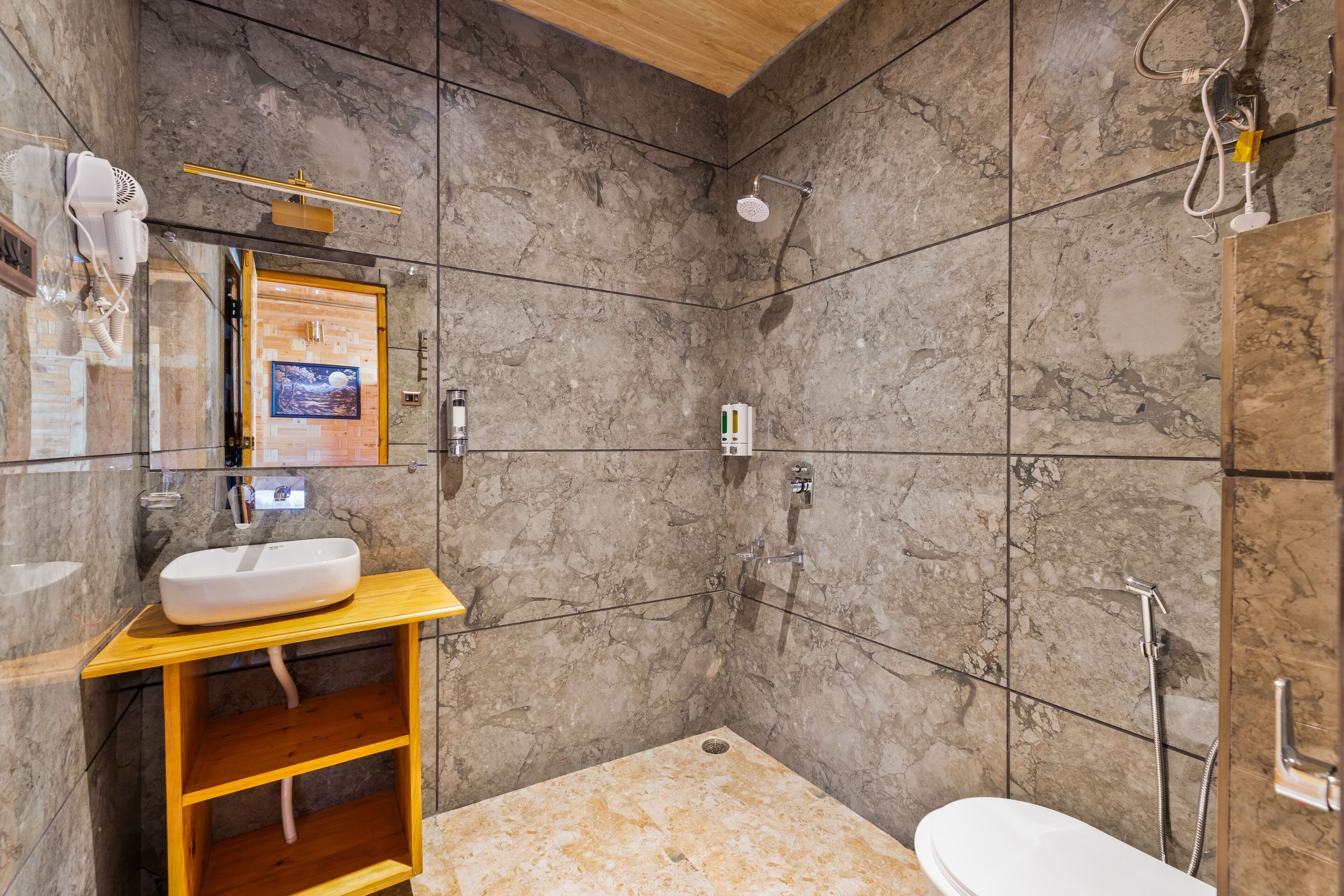 A modern bathroom with a marble shower, a wooden vanity, and a toilet.