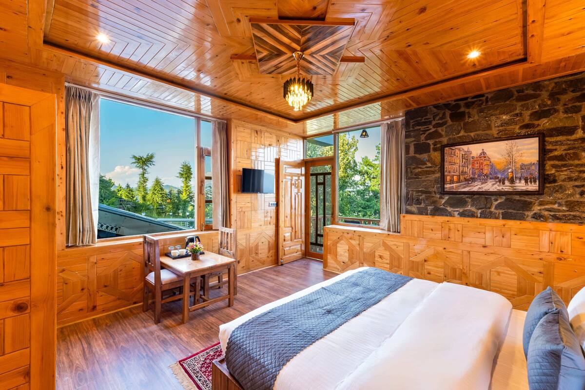 Un dormitorio de cabaña de madera con una cama grande, una mesa de comedor y una pared de piedra con un cuadro.