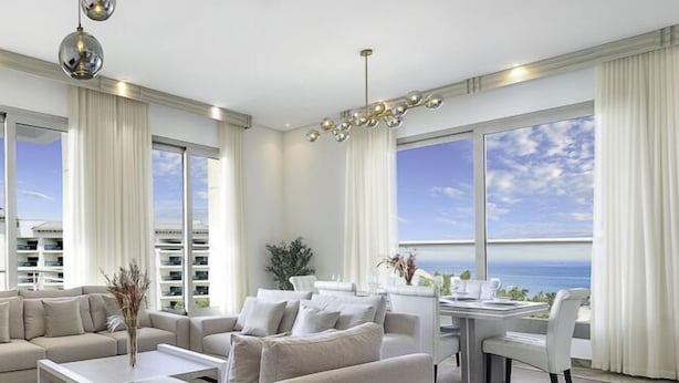 A modern living room with a large window, a dining area, and a sofa set. - LUX Dream Palm Atlantis Sea View Suite (Dubai)