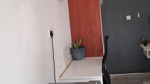 A modern kitchen with a grey refrigerator, a white countertop, a grey wall, a red accent wall, and a small potted plant. - Shalakwe Hills-Inn Guesthouse (Kasane)