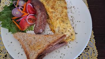 A plate with a sandwich, omelette, and salad on a lace tablecloth.