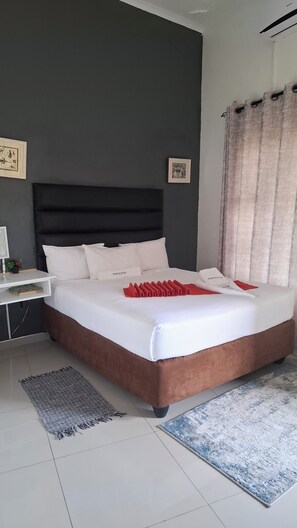 A neatly arranged bedroom with a large bed, a bedside table, a nightstand, and a window with curtains. - Shalakwe Hills-Inn Guesthouse (Kasane)