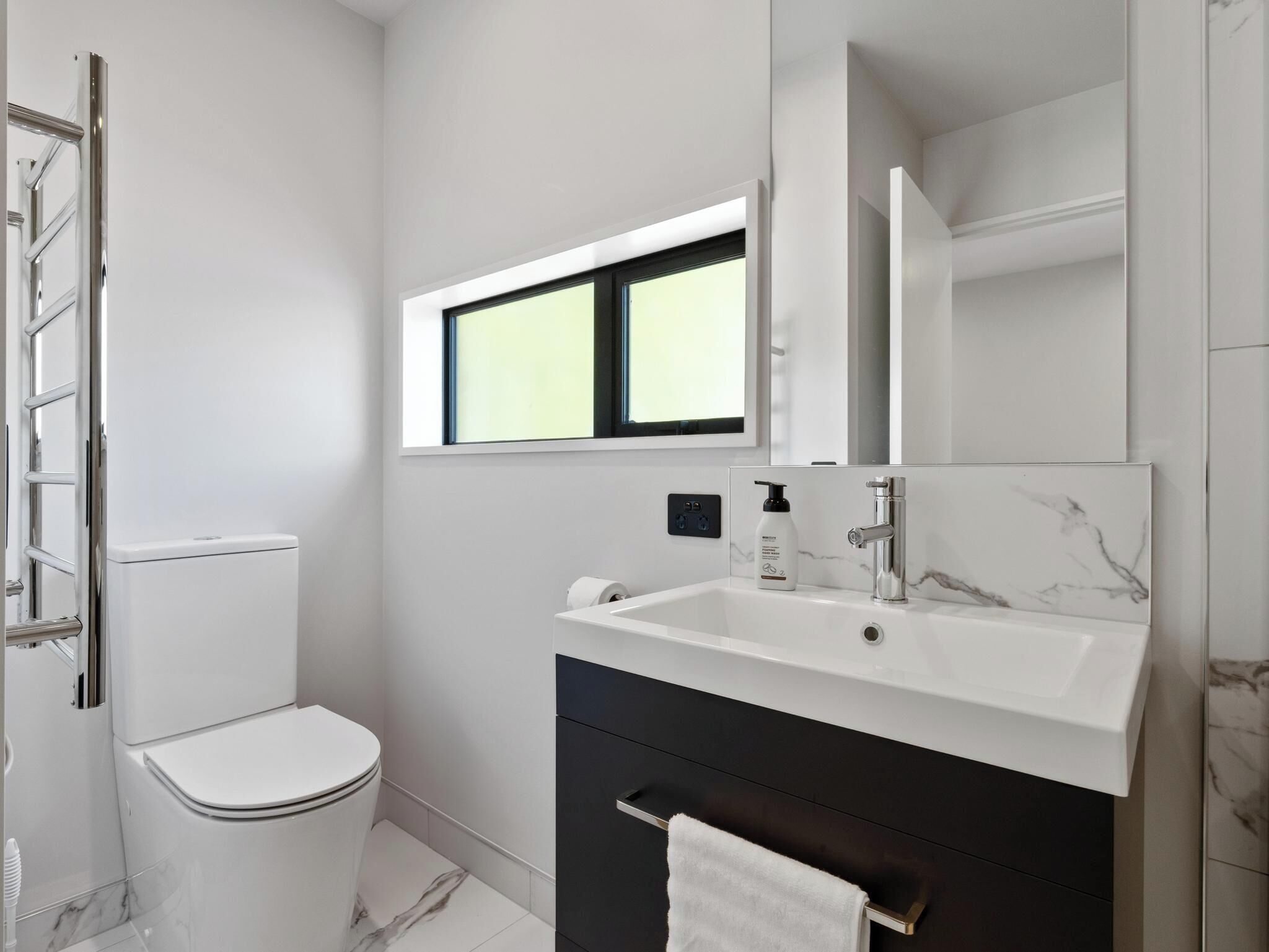 A modern bathroom with a toilet, sink, and mirror.