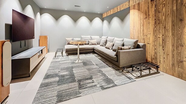 Een moderne woonkamer met een hoekbank, een flatscreen-televisie en een wand van hout.