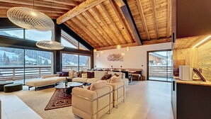 Un amplio salón con techo alto, ventanas grandes y una acogedora zona de estar.