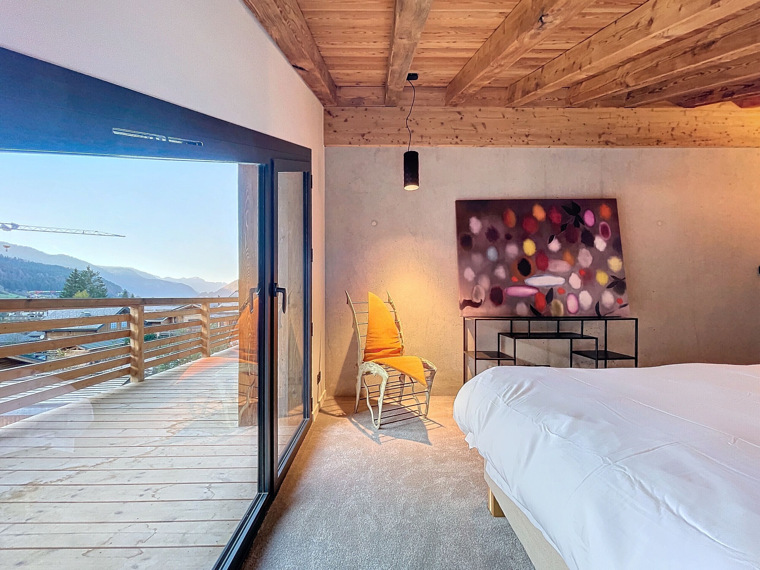 Une chambre à coucher avec un lit, une chaise, une table et un tableau.