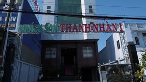 Un hôtel appelé « KHACH SAN THANHNANI », doté d’une architecture moderne, se distingue par son entrée imposante et le ciel dégagé qui s’étend au-dessus.