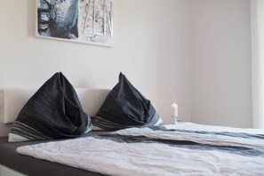 Restful retreat with a neatly made bed, bedside candle, and personal artwork.