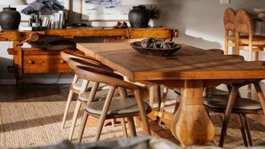 Un coin repas avec une table et des chaises en bois, un luminaire suspendu et des œuvres d’art accrochées au mur.