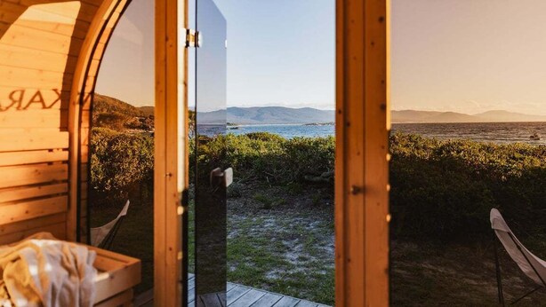Une cabane en bois offrant une vue sur une plage et des montagnes.