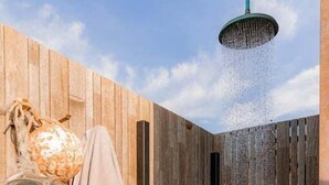 Une pièce en bois avec une douche, un globe en verre suspendu et une serviette.