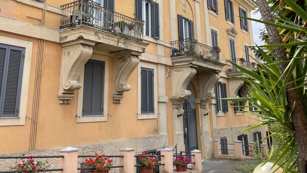 A building with multiple balconies, large windows with shutters, and potted plants along the walkway. - Welcome Rome by Interhome (Rome: Historical City Center)