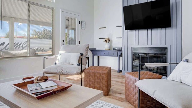 Un salon moderne avec un canapé, une table basse, un téléviseur fixé au mur et une cheminée.