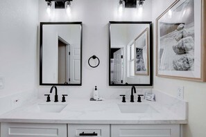 A modern bathroom with two sinks, black faucets, and a ring light above each mirror. - Cozy Modern 3BR Desert Style Home - Pool Fun! (North Las Vegas)