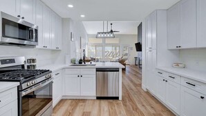 Une cuisine moderne avec des meubles blancs, une cuisinière en acier inoxydable et un lave-vaisselle.