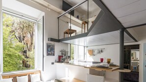 A modern kitchen with a dining area, large windows, and a view of greenery outside. - Marsicum by Interhome (Rome: Historical City Center)