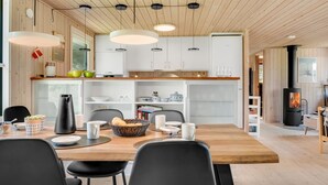 A modern kitchen with wooden ceiling beams, white cabinets, and a central island with seating. - "Rajna" - 500m to the fjord by Interhome (Vestervig)