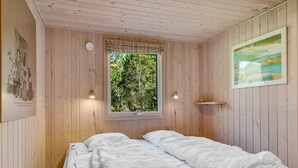A wooden room with a bed, a window with a view of trees, and a wall-mounted shelf. - "Rajna" - 500m to the fjord by Interhome (Vestervig)
