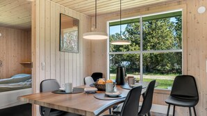 A wooden interior with a dining table, chairs, a coffee machine, and a window with a view of trees. - "Rajna" - 500m to the fjord by Interhome (Vestervig)