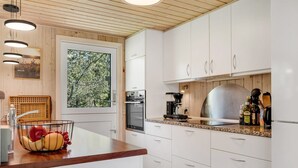 A modern kitchen with white cabinets, a wooden countertop, and a large window. - "Rajna" - 500m to the fjord by Interhome (Vestervig)
