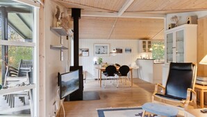 Ein gemütliches Blockhaus-Interieur mit Essbereich, Wohnzimmer mit Kamin und Küche.