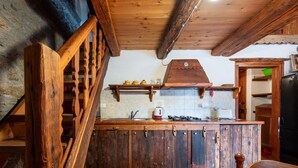 Una cocina rústica con armarios de madera, salpicadero de azulejos y una escalera de madera.