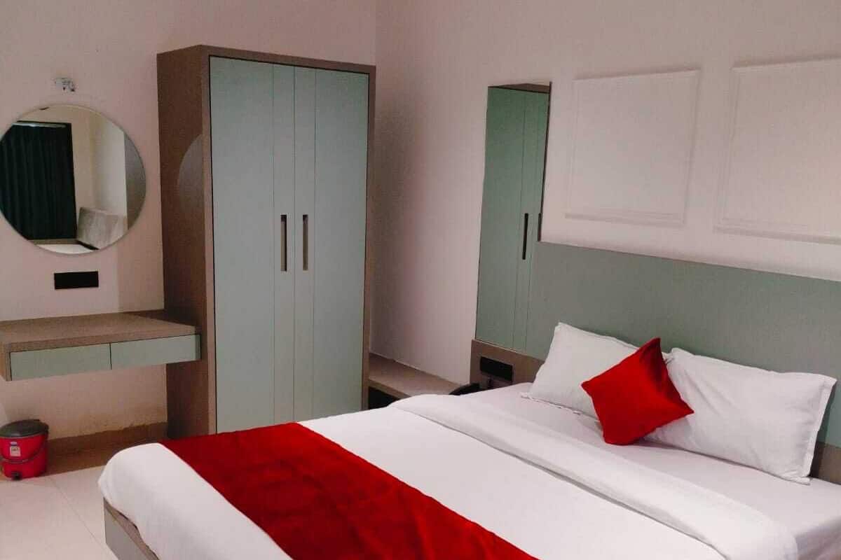 Ein Schlafzimmer mit einem Bett, einem Kleiderschrank, einem Spiegel und einer roten Decke.