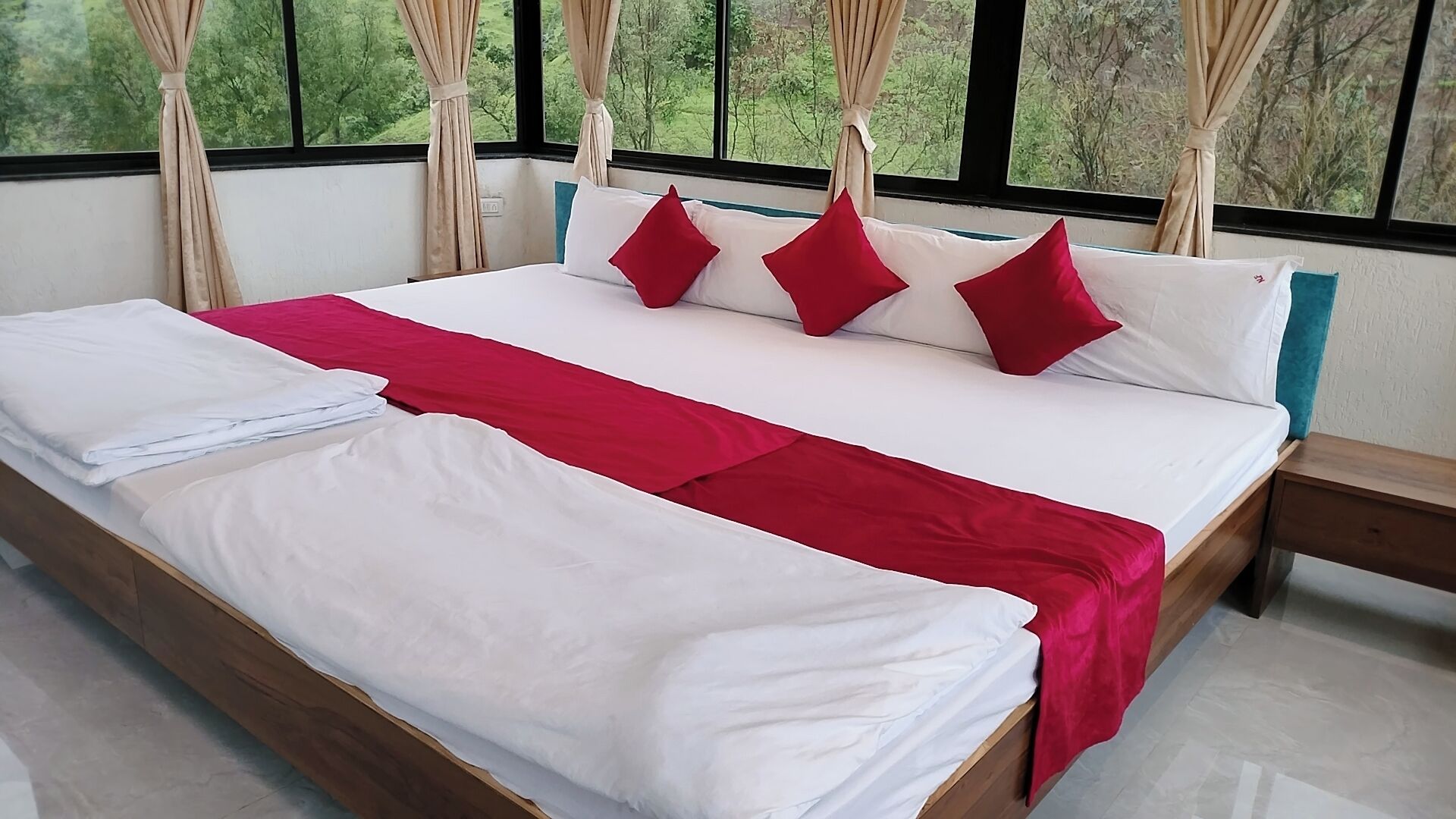 A bed with white and red bedding, a wooden headboard, and curtains.