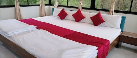 A bed with white and red bedding, a wooden headboard, and curtains.