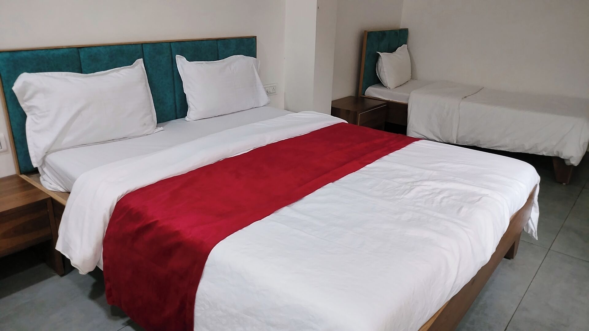 A hotel room with a large bed, a smaller bed, and a nightstand.