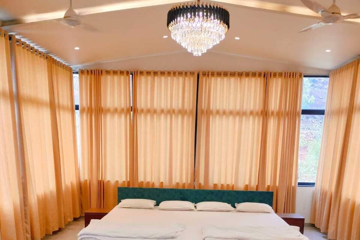Ein Schlafzimmer mit einem großen Bett, einem Kronleuchter, Vorhängen und einem Glastisch.