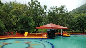 Une piscine avec un pavillon rouge, entourée d’une végétation luxuriante.
