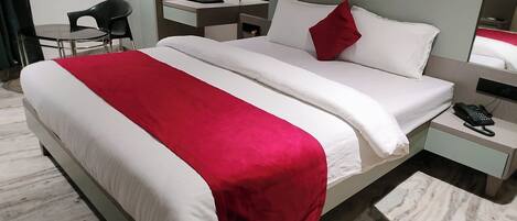 A hotel room with a bed, a desk, a chair, a nightstand, and a telephone.