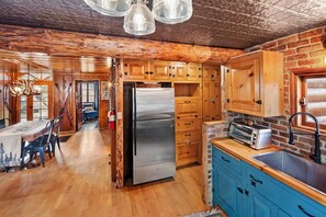 A rustic kitchen with wooden cabinets, a stainless steel refrigerator, and a blue countertop.