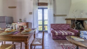A dining area with a wooden table set for a meal, a sofa, and a fireplace. - Marcigliana Cottage, Pool, Radicondoli (Radicondoli)